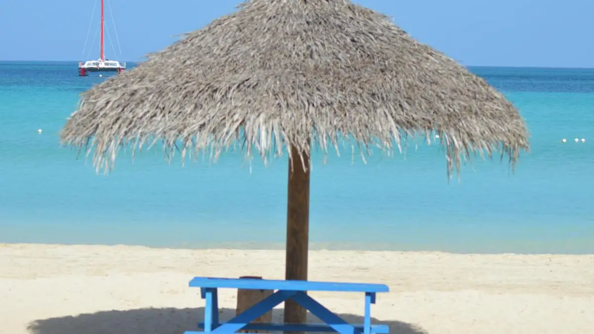 A palapa with a table on the white sand, facing the sea at Beachcomber Club Resort